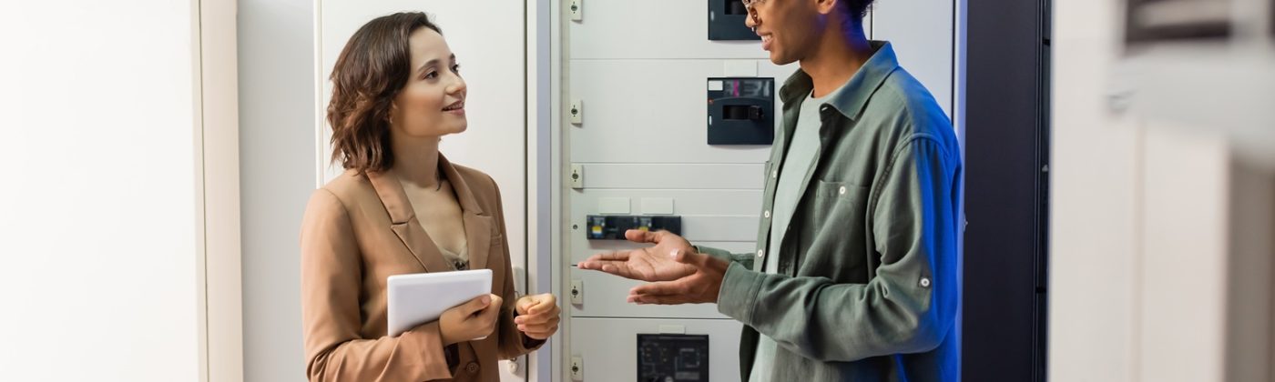 african american engineer pointing with hands while talking to colleague with digital tablet near